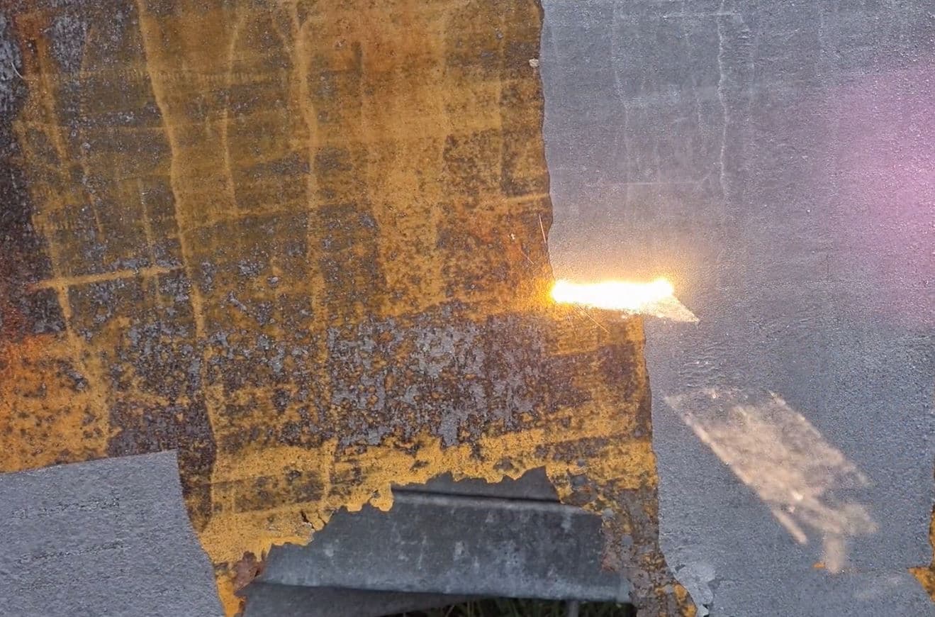 High-power laser coating removal on steel surface showing clean bare metal result
