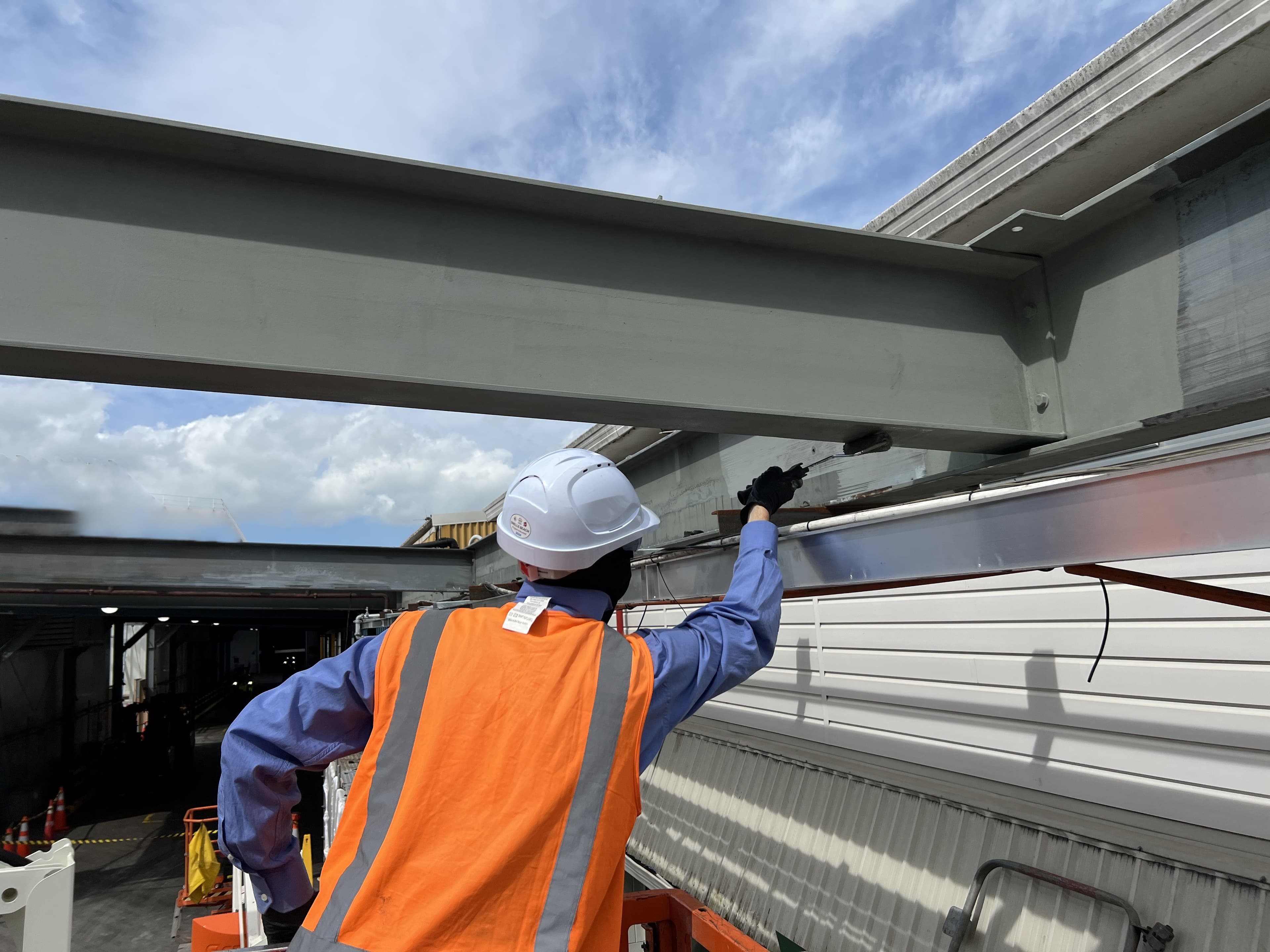 Laser blasting technician performing coating removal on steel beam infrastructure project